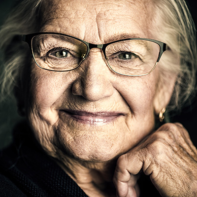 A senior smiling with her hand under chin.