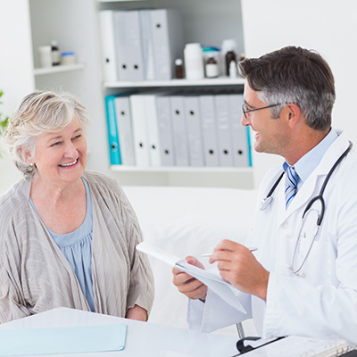 A senior laughing with a doctor in a doctors office.