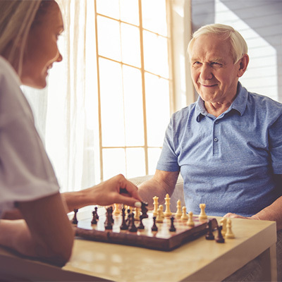 A senior and a young woman playing a game of chess.